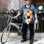 Ciclista con un perro colgado de un arnés