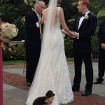 Perro lleva los anillos en la boda y se sienta en la cola del vestido de la novia